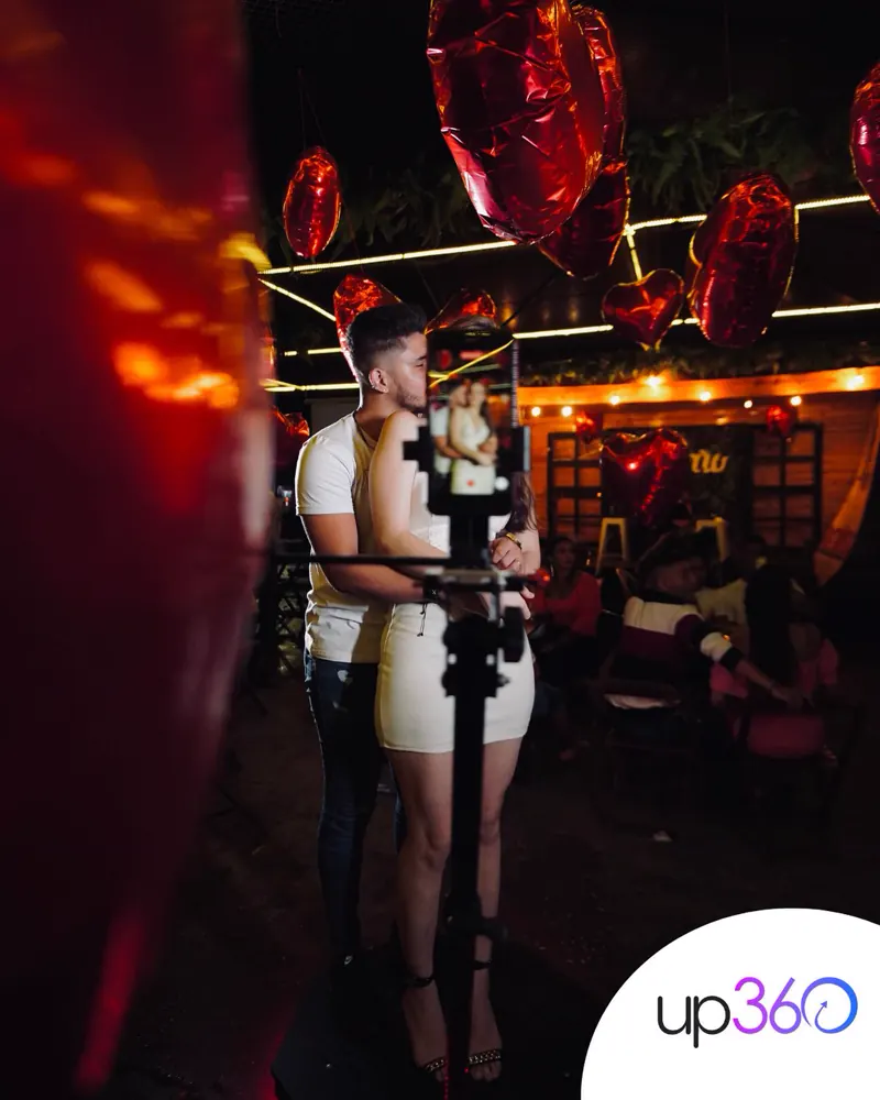 Casal abraçado gravando na Plataforma 360 em festa decorada com balões de coração